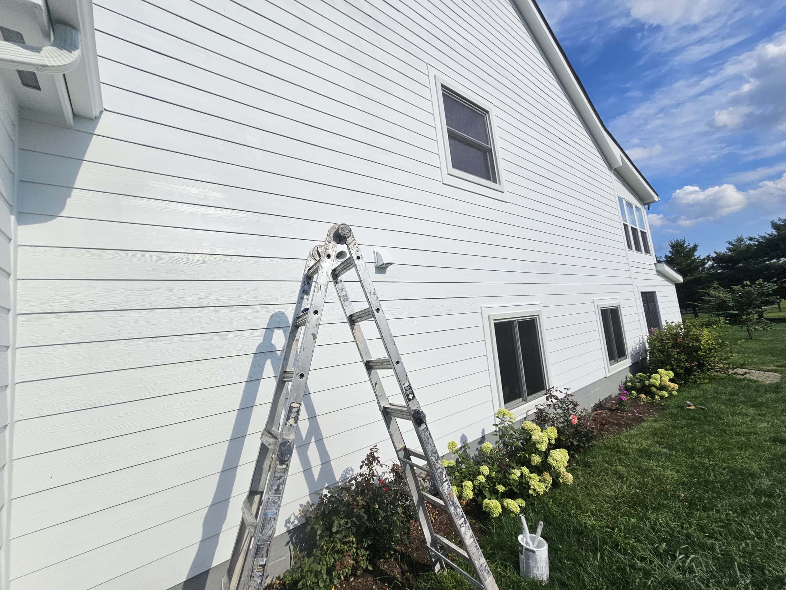 Bright white house exterior with ladder and gardening flowers in Columbus, Ohio.