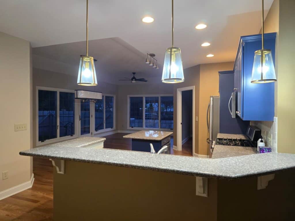 Brightened kitchen with vibrant blue cabinets, modern pendant lighting, and polished granite countertops.