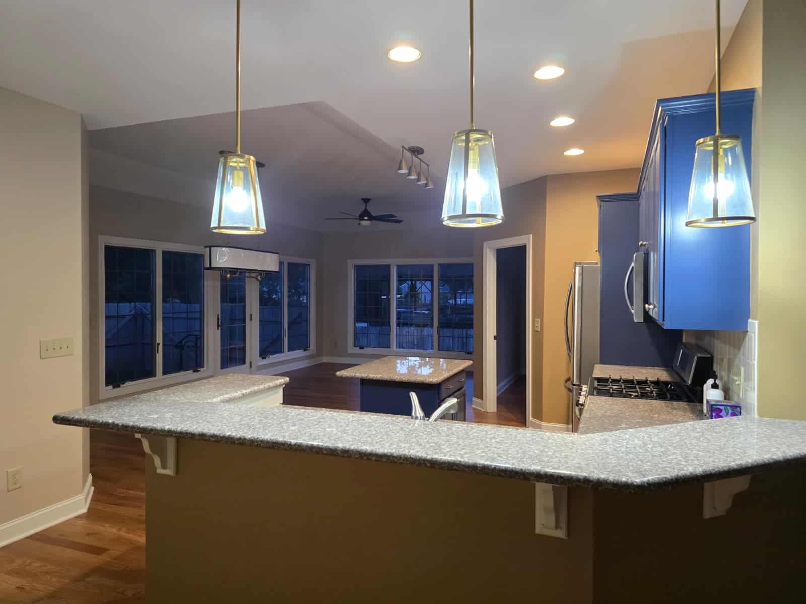 Brightened kitchen with vibrant blue cabinets, modern pendant lighting, and polished granite countertops.