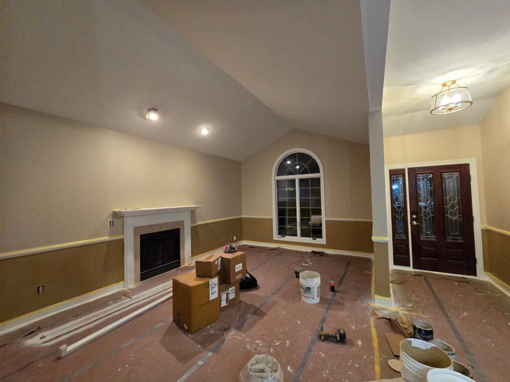 Bright living room with freshly painted beige walls, fireplace, and large arched window, painted by Columbus's top-rated interior painters.