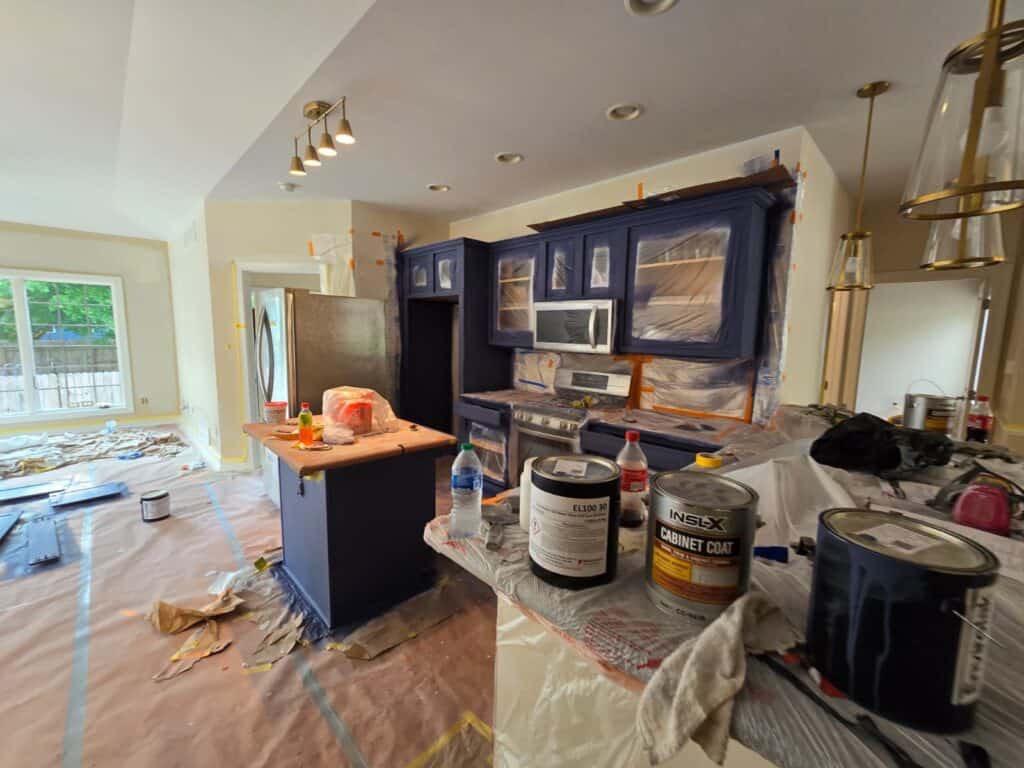 Brightly lit kitchen with blue cabinets and ongoing interior paintwork, showcasing professional house painting services.