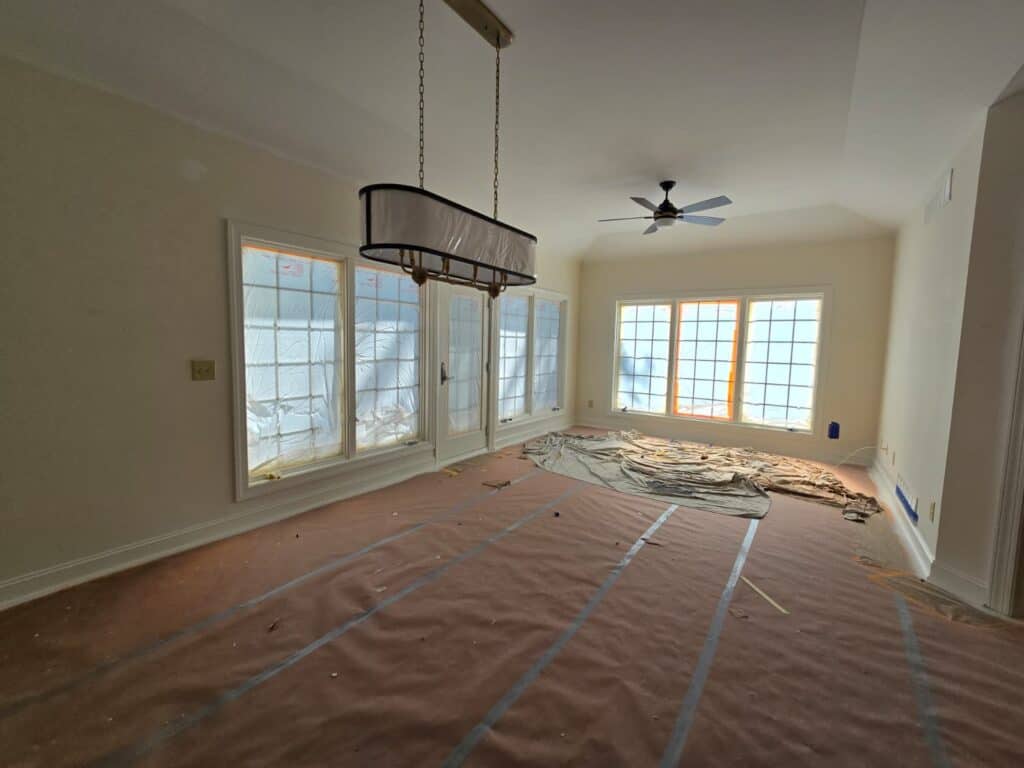 Bright, spacious room with freshly painted white walls, large windows, and modern lighting fixtures.