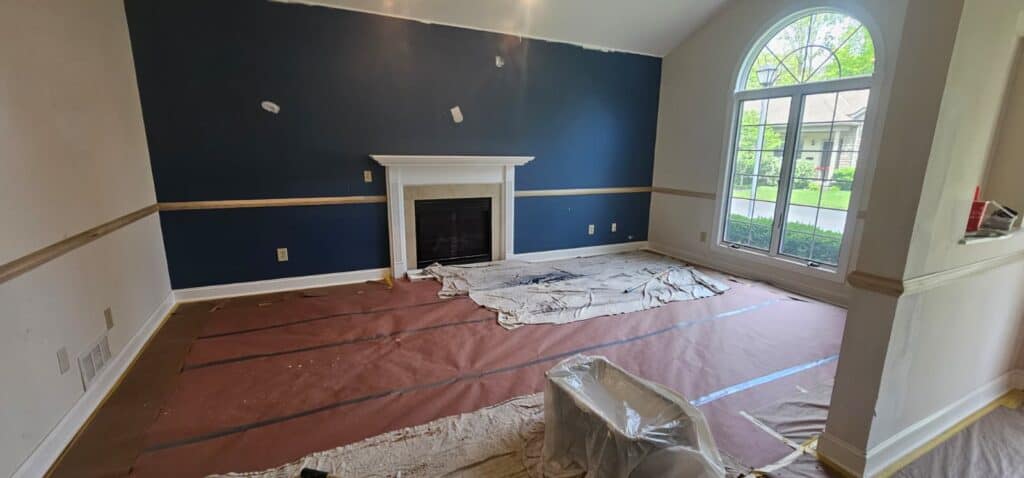 Bright living room with navy, white, and natural light, freshly painted walls, and elegant fireplace.