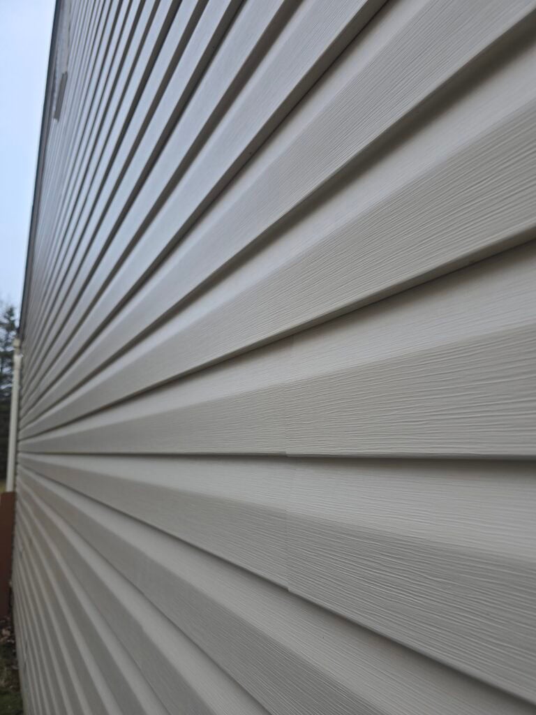 Residential vinyl siding installation close-up showing clean lap joints and wood-grain texture