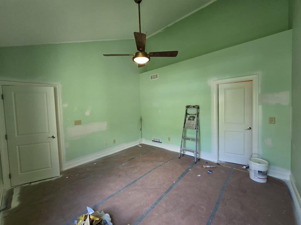 Sage green walls in Dublin Ohio room ready for interior repaint — ladder, drop cloths, drywall patches visible on green wall