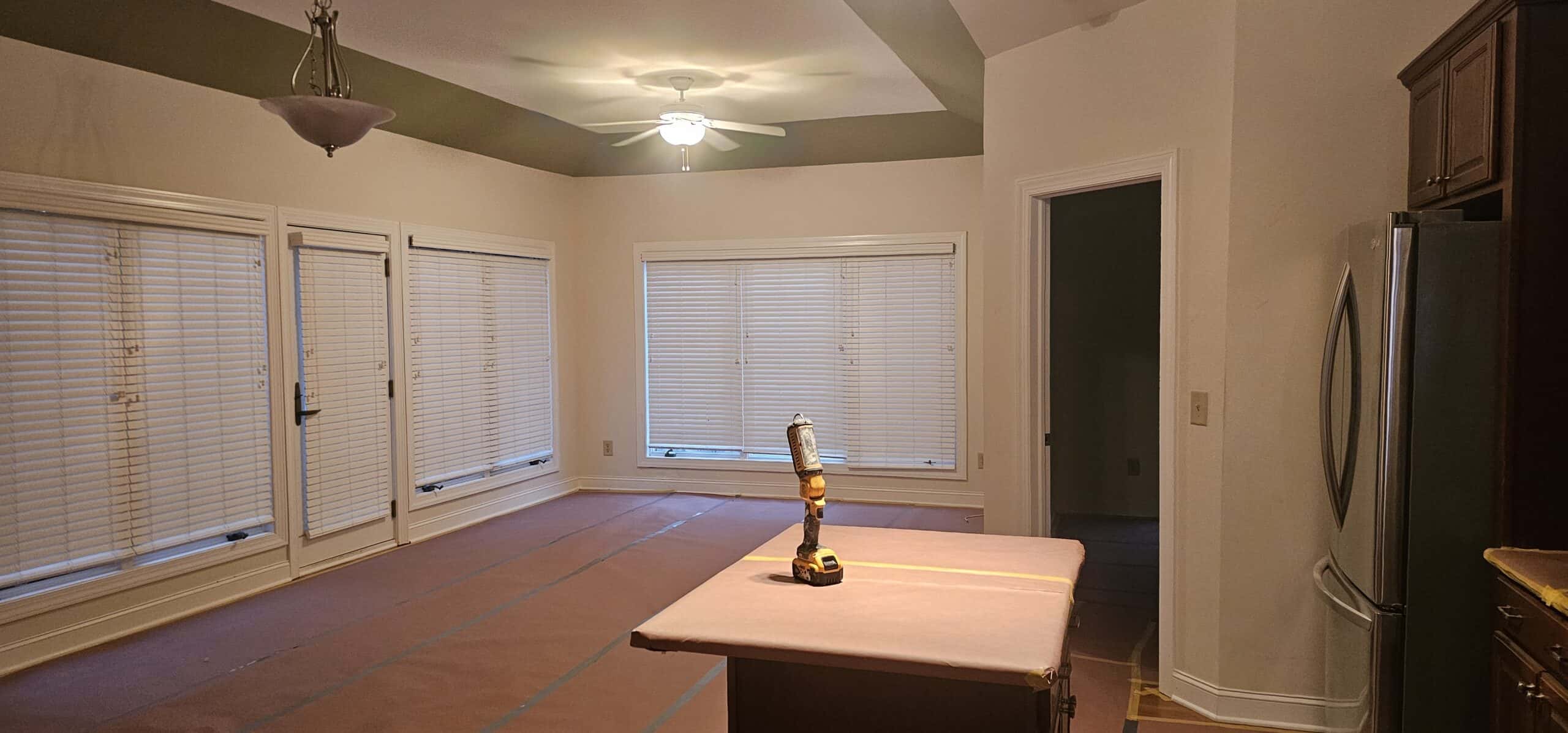 Dublin Ohio kitchen before PaintWerks cabinet refinishing — original dark cabinet visible upper-right, fridge in place, room emptied for paint prep